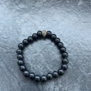 Svart pärlarmband med metallpärla - Elegant svart pärlarmband med en unik metallpärla som detalj. Perfekt för att ge en stilren touch till din outfit.