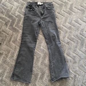Grå bootcut jeans från 157 - Snygga grå bootcut jeans från lager 157 i storlek 140. De har en klassisk femficksdesign och en bekväm passform. Perfekta för en avslappnad stil med en touch av 90-tal. Jag vill inte ha dessa jeans då jag har växt ur de.❤️