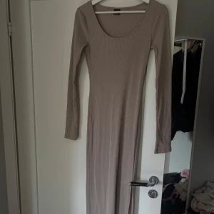 Beige ribbad långklänning - Snygg beige långklänning med ribbad struktur och långa ärmar från Gina tricot. Använd en gång.