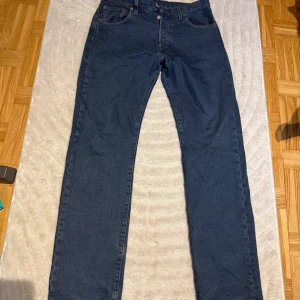 Levis 501 - Säljer ett par klassiska blå Levi's 501 jeans. De har en rak passform och är tillverkade i slitstarkt denim. Byxorna har fem fickor och knappar i gylfen. Perfekta för en tidlös stil. W30 L32