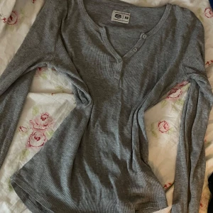 Grå tröja från Crocker - Säljer en grå tröja från Crocker i storlek XS. Tröjan har långa ärmar och en knappdetalj vid halsrigningen.