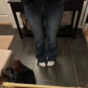 Blå bootcut jeans - Säljer ett par klassiska blå bootcut jeans. De har en snygg passform och är perfekta för en avslappnad stil. Jeansen har en traditionell femficksdesign och en bekväm midja.  Tyvärr är dom slitna vid hälarna från tidigare användare och därav så pass rabatterat pris!  Passformen är mer som en 36 än 38, vilket är storleken på byxorna! 