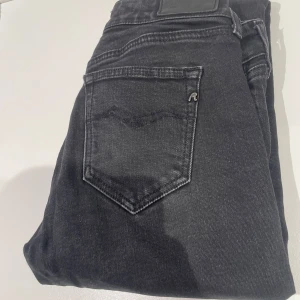 Svarta jeans från Replay - Snygga svarta jeans från Replay med klassisk femficksdesign och diskret logga på bakfickan. Perfekta för en stilren look. De har en knappgylf och är tillverkade i ett bekvämt material som ger en bra passform.