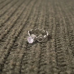 Crown Circle - Silver Ring with Stone - US storlek 7, diameter 17,3 mm, omkrets 54,4 mm. En elegant ring med smà kronliknande motiv som ramar in den gnistrande stenen. Den justerbara designen kombinerar sofistikation och komfort.