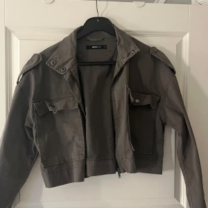 Kort jacka - Snygg grå croppad jacka från Gina Tricot med dragkedja och knappar. Bra skick inga defekter. Säljer för 80kr + frakt eller lägg prisförslag🫶🏻