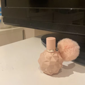 Parfym med rosa flaska och fluffig boll - Snygg parfym i en ljusrosa, geometriskt formad flaska med en fluffig boll som dekoration. Perfekt för den som gillar en söt och lekfull design.