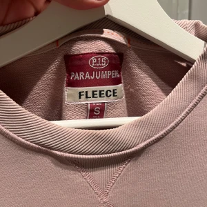 Rosa fleece tröja från Parajumpers - Säljer en mjuk och bekväm rosa fleece tröja från Parajumpers (färgen är mer rättvis på första bilden). Tröjan har långa ärmar och ett tryck med märkesnamnet på framsidan. Det finns även en snygg patch på ärmen. Perfekt för kyliga dagar. Köpt på nk i Göteborg. Endast tvättad en gång! 