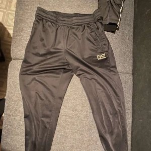 Svarta mjukisbyxor från EA7 Emporio Armani - Ett par snygga mjukisbyxor från EA7 i nyskick!! Helt oanvända (endast testade), lite dåliga bilder men skriv för fler! Är i storlek M men passar även S, väldigt sköna att ha till vardags!!