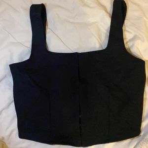 Svart linnetopp från H&M Divided - Svart korsett topp från H&M Divided. Perfekt för både vardag och festtilfälle. Ny utan prislapp.
