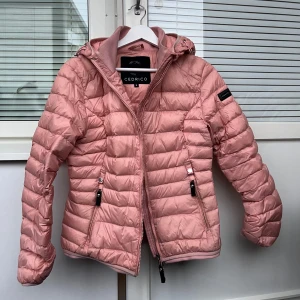 Cedrico Lättviktsjacka - Suuuperfin lättviktsjacka ifrån Cedrico! Den är inte bulkig men håller fortfarande värmen superbra då 90% Dun 10% Fjäder! Den är använd och har lite missfärgningar vid fickorna och på någon mer plats se bild 5. Cedrico märket är lite repigt men annars är jackan i bra skick och har många år till att ge😇💓 Skulle säga att den passar en XS också💓