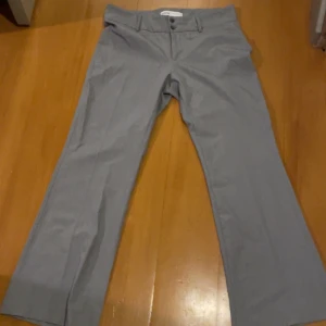 Grå kostymbyxor - Snygga grå kostymbyxor med bootcut  och knappar i midjan. Perfekta för en stilren look. De är oanvända och otroligt fina men passade tyvärr inte, dem har låg midja 