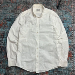 Vit skjorta från Acne - Snygg vit skjorta från Acne med klassisk krage och knappar framtill. Skjortan har långa ärmar och en diskret broderat A. Perfekt för en stilren look. Fint skick, storlek 48 (Typ S-M herr).                Our legacy, shirt, filippa k, samsoe samsoe, acne studios