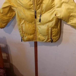 Gul pufferjacka med dragkedja - Snygg gul pufferjacka med dragkedja och praktiska fickor. Perfekt för kyliga dagar med sin vadderade design. Jackan har långa ärmar och en bekväm passform.