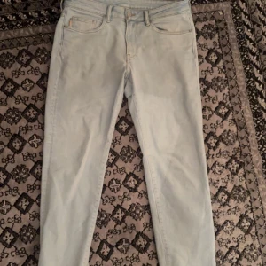 Ljusblå jeans från H&M - Säljer ett par ljusblå jeans från H&M i straight regular fit. De har en klassisk design med fem fickor och knappgylf. Perfekta för en avslappnad stil.