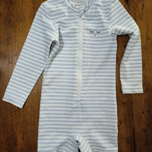 Baby Lively Swimsuit - Worn twice. Perfect condition. My son outgrew it too quick unfortunately. Very cute, old-fashioned swimsuit. 50 SPF. ORIGINAL PRICE: 645 kr.                                   Sam Long Sleeve Swimsuit kommer i en rand i blå och vit, med långa ärmar och dragkedja framtill. Detta är ett måste i sommargarderoben för din lilla! • UPF 50+ • Randigt tryck MATERIAL OCH TVÄTTRÅD: • 82 % polyester, 18 % elastan • Maskintvätt