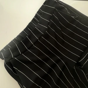 Kostymbyxor  - Kritstrecksrandiga kostymbyxor med tak passform. Känns som tights i materialet. Har fickor