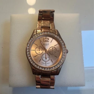 Klocka - En guld/ champagne färgad klocka. Väldigt elegant och oanvänd. Den går att ändra storlek i affär men tycker den har en passande storlek som bör passa dom flesta. Väldigt fin och äkta.