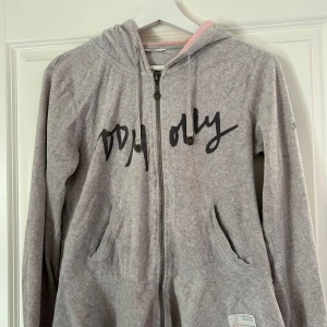 Grå velourhoodie från Odd Molly - Säljer en mysig grå velourhoodie från Odd Molly med dragkedja och tryck framtill. Den har en rosa insida i luvan och ett broderat märke på ärmen. Perfekt för en avslappnad stil. Tröjan är i fint skick, vid frågor och funderingar hör av er! Jag svarar så fort jag kan!🩷