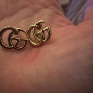 Guldörhängen  med bokstäver  - Snygga guldörhängen med klassisk  bokstäver. Helt oanvända. Perfekta för att ge en lyxig touch till din outfit. Dessa örhängen är stilrena och tidlösa, vilket gör dem till ett utmärkt val för alla tillfällen.