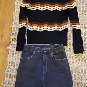 Mönstrad tröja från & Other Stories - Säljer en snygg mönstrad tröja från & Other Stories. Tröjan har ett coolt zigzag-mönster i brunt, vitt och orange på en svart bas. Den är långärmad och perfekt för höst och vinter. Passar utmärkt till jeans eller kjol!