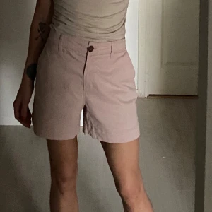 Ljusrosa/gammelrosa shorts med knappdetalj - Säljer ett par ljusrosa shorts med knapp och dragkedja framtill. De har en klassisk design med fickor både fram och bak. Perfekt längd och superbekväma. Sålde snabbt slut på hemsidan . 