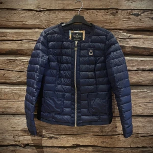 Mörkblå dunjacka från Morris - Snygg mörkblå dunjacka från Morris Lady med dragkedja framtill. Jackan har en quiltad design och långa ärmar, perfekt för kyligare dagar. Den är stilren och enkel att matcha med olika outfits. Från ett gjir- och rökfritt hem.