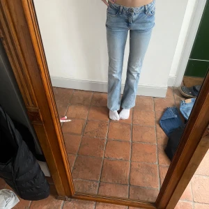 Ljusblå bootcut jeans - Snygga ljusblå lowwaist bootcut jeans! Små slitningar längst ner vid hälen som visas på bild 3 Midjemått:33 det går att justera midjan! Innerbenslängd:66 