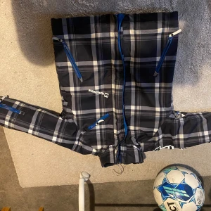 Rutig jacka från Wellensteyn - Snygg rutig jacka från Wellensteyn med blå och vita detaljer. Jackan har dragkedja och flera praktiska fickor. Perfekt för kyligare dagar med sin långärmade design.