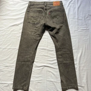 Grå jeans från Levi's - Snygga grå jeans från Levi's med klassisk femficksdesign och knappgylf. De har en rak passform och är tillverkade i ett slitstarkt denimtyg. Perfekta för en avslappnad stil. Modell 502. Bara att höra av sig vid frågor//Carl