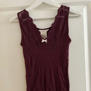 Burgundy ribbad linnetopp från Odd Molly - Säljer en burgundy färgad ribbad linnetopp från Odd Molly med spetsdetaljer och en söt rosett framtill. Toppen är ärmlös och har en v-ringad design som ger en feminin touch. Perfekt för att lägga till lite stil i din garderob! Jättefin topp i bra skick som är sparsamt använd. Vid frågor och funderingar hör av er, jag svarar så fort jag kan!🩷