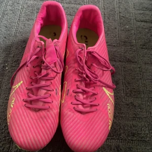 Nike fotbollsskor - Säljer ett par rosa Nike Mercurial vapor Academy, nypris 1000!!!. Fungerar både på konstgräs och naturgräs. Storlek 43, UK 8,5. Lägre pris kan diskuteras. Skorna är använda men är i hyfsat skick.
