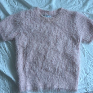 Rosa fluffig tröja från Zara - Säljer en supermjuk och fluffig rosa tröja från Zara. Den har korta ärmar och en mysig textur som ger en unik look. Perfekt för att hålla sig varm och stilren under kyligare dagar. Passar perfekt till jeans eller kjol för en avslappnad stil. skriv om ni har frågor. 