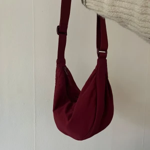 Vinröd axelväska med dragkedja - Vinröd praktisk axelväska med justerbar rem och dragkedja.