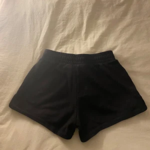 Svarta shorts från Champion - Snygga svarta shorts från Champion med elastisk midja för en bekväm passform. Perfekta för träning eller en avslappnad dag. Diskret Champion-logga på sidan ger en stilren touch.