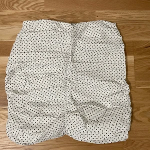 Vit prickig kjol från MNG - Säljer en söt vit kjol med svarta prickar från MNG. Kjolen har en dragkedja på sidan och är perfekt för en somrig look. Den är lätt och luftig, vilket gör den idealisk för varma dagar.