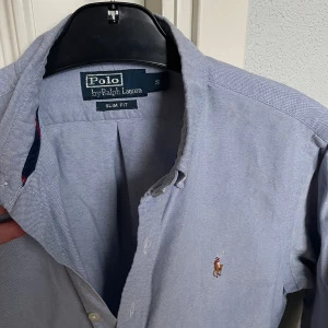 Blå skjorta - Polo Ralph Lauren - Blå skjorta från Polo Ralph Lauren. Perfekt under en tröja. Storlek: S, slim fit. Skick:9/10, väldigt fint skick. Kontakta oss för fler bilder eller info!