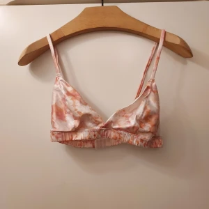 Rosa och vit bralette från Bikbok  - Säljer en söt bralette från Bikbok i rosa och vitt mönster. Den har justerbara axelband och en mjuk resår under bysten för extra komfort. Perfekt för en avslappnad stil.