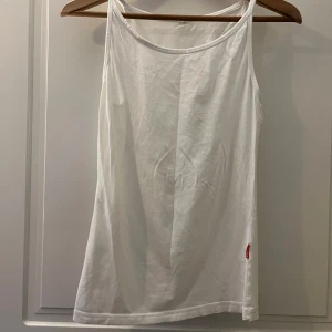 Vit linnetopp  - Säljer en klassisk vit linnetopp . Perfekt för varma sommardagar med sin enkla och stilrena design. Toppen har smala axelband, storlek S
