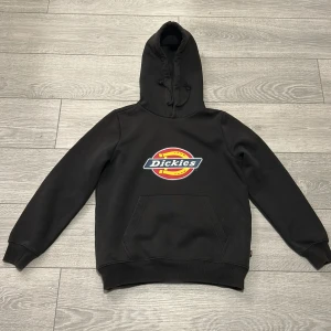 Svart hoodie från Dickies - Säljer en klassisk svart hoodie från Dickies med deras logga på bröstet. Tröjan har en bekväm passform med långa ärmar och en praktisk magficka. Använt ett fåtal gånger. 