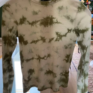 Grön tröja - Säljer en  tröja med tie-dye mönster i olika gröna färger. Tröjan har långa ärmar och en hög krage. Passar bra till jeans eller kjol. Köpt på New Yorker
