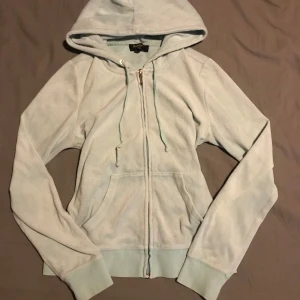 Ljusblå hoodie från Juicy Couture - Säljer en ljusblå hoodie från Juicy Couture med dragkedja och huva. Tröjan har långa ärmar och en snygg detalj med små pärlor på ryggen. Perfekt för en avslappnad stil. 💙