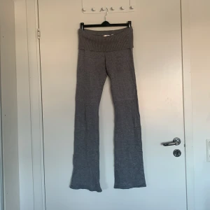 Grå stickade byxor från Gina Tricot - Snygga grå stickade byxor från Gina Tricot med ribbad midja. Perfekta för en avslappnad stil. Byxorna har en bootcut-stil som ger en trendig look.