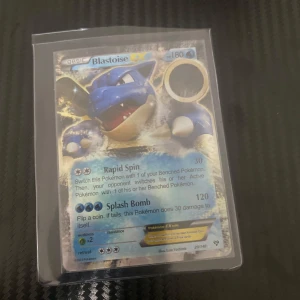 Blastoise EX Pokémonkort - Säljer ett Blastoise EX Pokémonkort med 180 HP. Kortet har attacker som Rapid Spin och Splash Bomb. Perfekt för samlare eller spelare som vill förstärka sin kortlek. Kortet är i en skyddande plastficka.