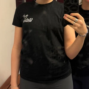 Svart t-shirt med tryck - Säljer en svart t-shirt med ett tryck på bröstet. T-shirten har en klassisk rund hals och korta ärmar. Perfekt för en avslappnad stil. Hör av dig vid intresse!