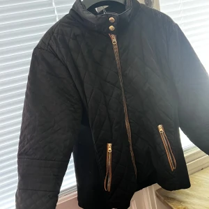 Svart quiltad jacka från Vero Moda - Säljer en svart quiltad jacka från Vero Moda med dragkedja och knappar. Jackan har långa ärmar och två fickor med dragkedjor. Perfekt för kyligare dagar. (Sliten vid halsen).