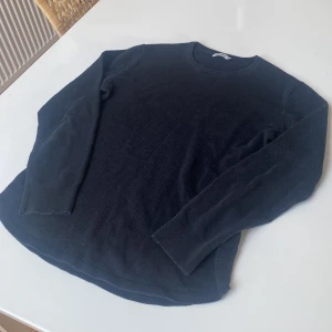 Stickad tröja  - Snygg svart tröja från J.Lindeberg i storlek M. Tröjan har en klassisk design med rund hals och långa ärmar. Perfekt för en stilren look. Storlek M men sitter mer som en S