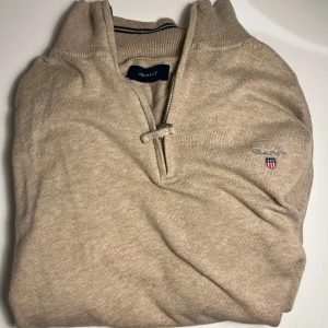 Beige tröja med dragkedja från Gant - ✅STEAL✅vi säljer nu en stilren beige tröja från Gant med dragkedja vid halsen. Tröjan har långa ärmar och ett diskret broderat Gant-emblem på bröstet. Perfekt för en avslappnad och snygg look. Passar perfekt att dra på sig inför sommar och vårkvällar!🤗 inköpt ny för 1200kr i Göteborg under hösten vi säljer den för endast 420kr🤩🤗 super skick!