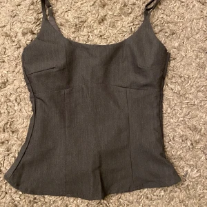 Grå linnetopp från Hm Divided - Säljer en stilren grå linnetopp från Divided i nytt skick. Toppen har justerbara axelband och en figurnära passform som passar perfekt till både vardag och fest. Materialet känns mjukt och bekvämt mot huden.  Säljer pga att den inte passade mig 