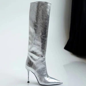 Silvriga stövlar från Anny Nord - Snygga och glittriga silvriga stövlar i vegan läder med spetsig tå och hög klack. Perfekta för en festlig kväll eller nyårsfirande. De är i nytt skick och kommer i originalförpackning. Ett måste för den som vill sticka ut! Jag brukar ha 39-39,5 men köpte dessa i 40 för att ha lite utrymme. 