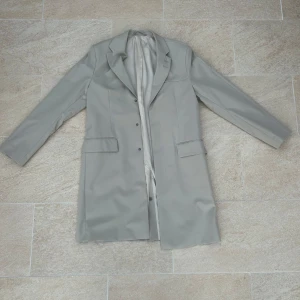 Grå kappa från Tiger of Sweden - Säljer en stilren grå kappa från Tiger of Sweden. Perfekt för höst och vår, och ger en elegant touch till vilken outfit som helst. Passar både till vardags och mer formella tillfällen. Skriv om ni har några frågor!